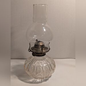 A vintage-style glass oil lamp, with a clear, ribbed glass reservoir base.